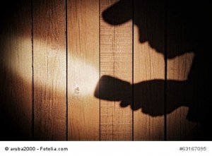 Human silhouette with flashlight in shadow on wood background, X